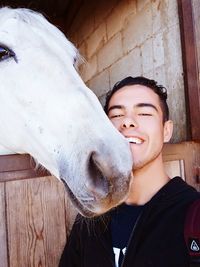 Portrait of happy man by horse at stable