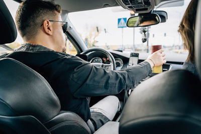 Side view of young woman sitting in car