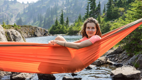 Woman is relaxing in a hammock at the alpine lake on local vacation