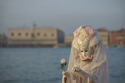 Woman in carnival costume standing against river in city