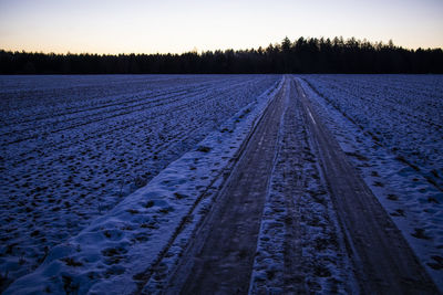 View of tire tracks on snow covered land