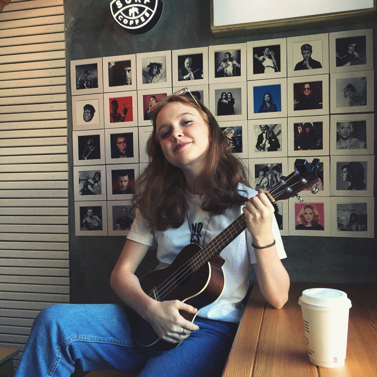 sitting, guitar, looking at camera, string instrument, music, portrait, one person, musical instrument, home interior, real people, leisure activity, young adult, smiling, lifestyles, indoors, casual clothing, front view, playing, emotion, plucking an instrument