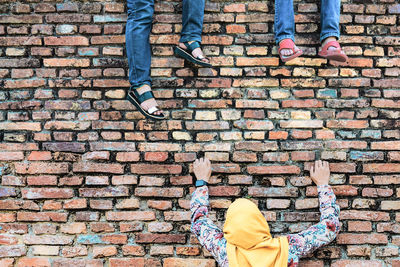 Low section of people standing on brick wall