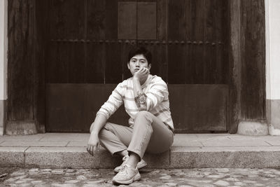 Portrait of woman sitting against building