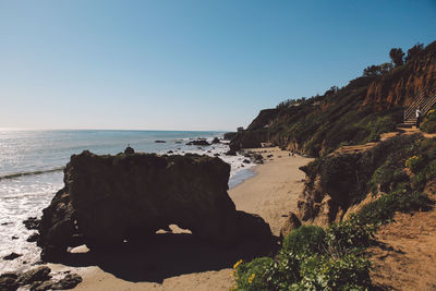 Rock formation on beach against clear sky