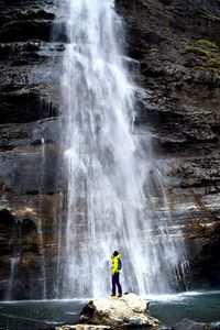 Full length of man standing against waterfall