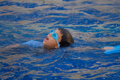 Boy wearing goggles swimming in pool