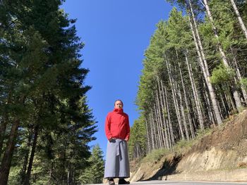 Man standing by trees in forest against sky