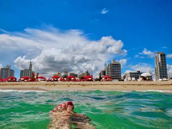 Low section of person in swimming pool against buildings in city