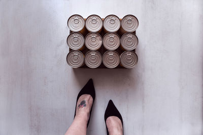 Low section of woman standing by tin cans