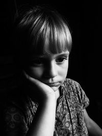 Close-up of girl with hand on chin against black background