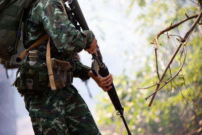 Midsection of army soldier holding rifle