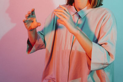 Midsection of woman holding orange while standing against wall at home