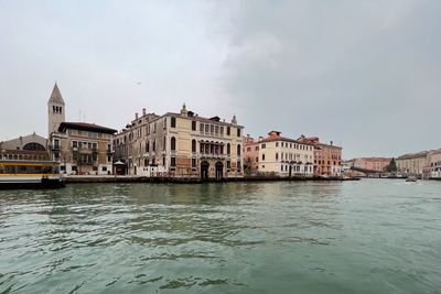 Buildings by river against sky