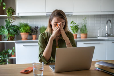 Businesswoman using laptop while sitting on table