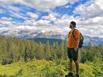 Rear view of man looking at mountains against sky