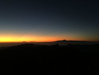 Scenic view of silhouette mountains against orange sky