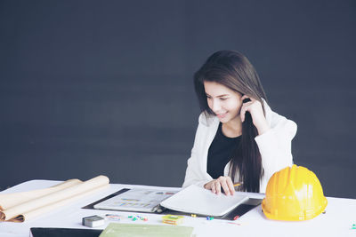 Young woman looking away while sitting on table