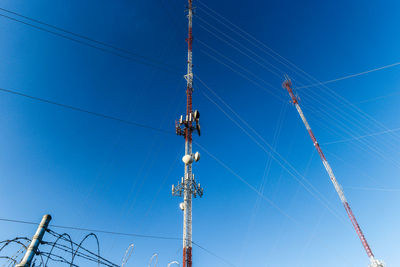 Low angle view of electricity pylon against blue sky