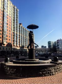 Fountain in city against clear sky
