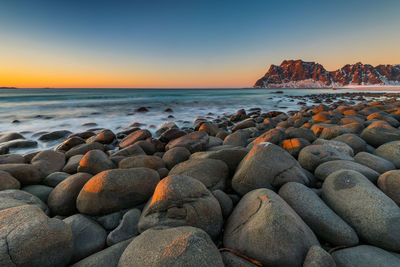 Rocks at beach against sky during sunset