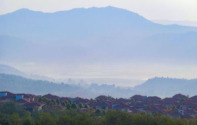 Scenic view of townscape by mountains against sky