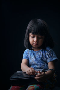 Cute girl holding radio against black background