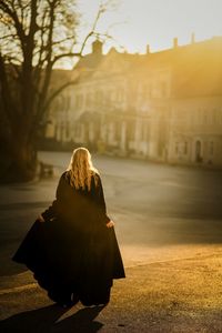 Rear view of woman with umbrella walking in city