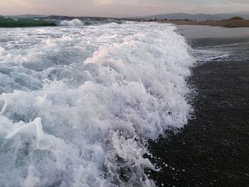 Waves splashing in sea against sky