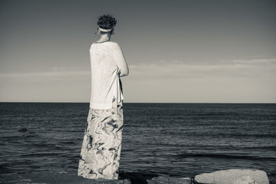 Rear view of woman standing by sea against sky