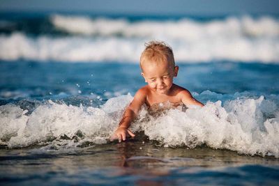 Cute boy playing in waves at beach