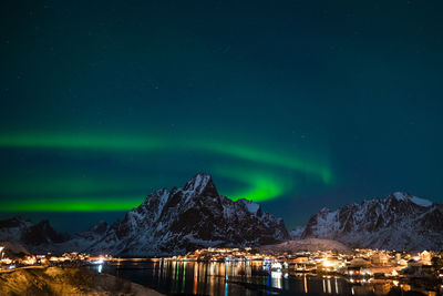 Scenic view of illuminated snowcapped mountains against sky at night