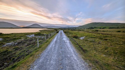 Empty rural road by lake and mountains at connemara national park, galway, ireland