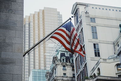 Low angle view of american flag against buildings in city