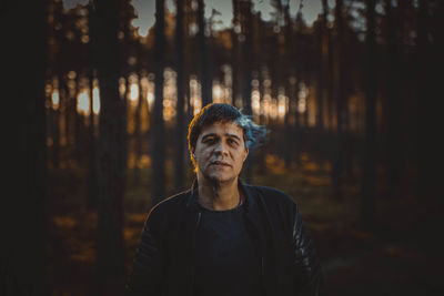 Mid adult man smoking in forest during sunset