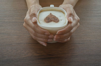 Low section of woman holding coffee cup on table