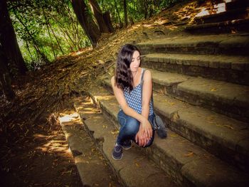 Young woman sitting on steps in forest