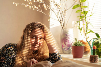 Portrait of smiling young woman sitting in front of the window at home