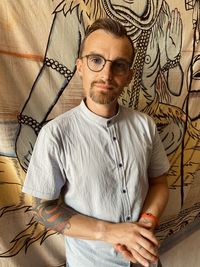 Portrait of young man standing against wall