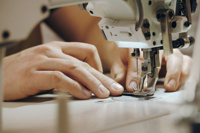 Tailor sewing at workplace. man hands sewing on machine at his studio. tailoring concept. close-up