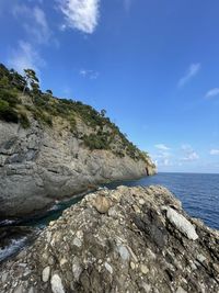 Rock formation on beach against blue sky