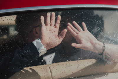 Cropped image of hand on wet window