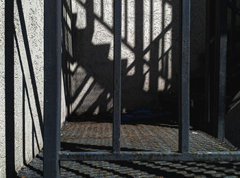 Shadow of metal fence on wall of building