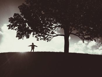 Silhouette man on tree against sky