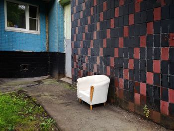 Empty chair against wall of building