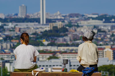 Rear view of man and woman looking at cityscape