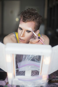 Young man applying drag makeup