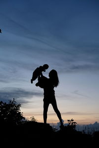 Silhouette couple standing against sky during sunset