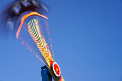 Low angle view of illuminated lighting equipment against clear blue sky