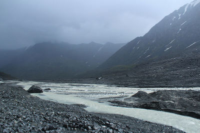 Akkol river among mountain ranges in a high mountain gorge in altai with fog and sunlight in summer